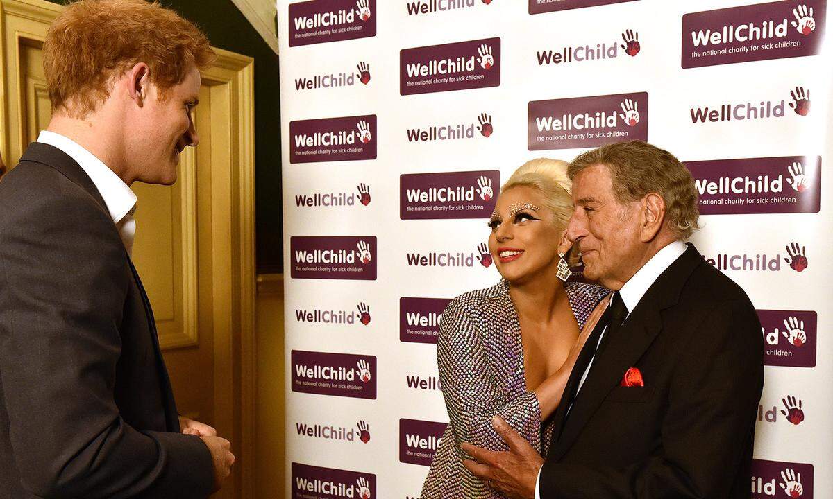 Etwas eingeschüchtert wirken die Musikgrößen Lady Gaga und Tony Bennett bei einem Charity-Konzert im Juni 2015 in London im Angesicht königlichen Blutes. Prinz Harry nimmt‘s gelassen.