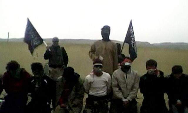 Still frame from video obtained from a social media website shows three rebels, two of them carrying Jabhat al-Nussra flags, stand behind a row of 11 kneeling men prior to executing them in what is said to be Deir al-Zor