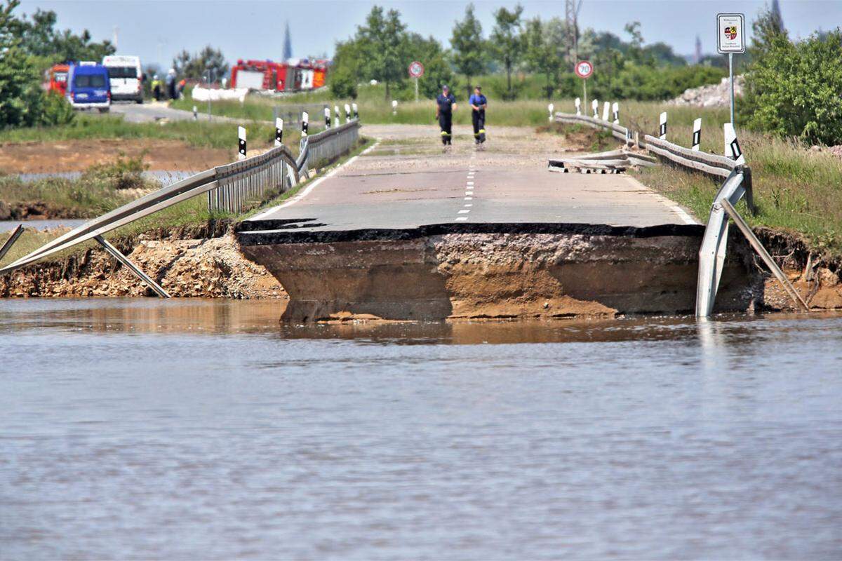 In Löbnitz hat der Fluss Mulde eine Straße mit sich mitgerissen. Feuerwehrmänner begutachten den Schaden.