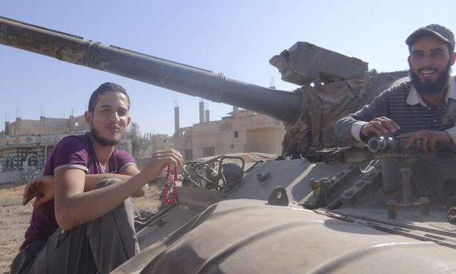 Free Syrian Army fighters are seen at a tank that belonged to forces loyal to Syria's President Bashar al-Assad in Deraa