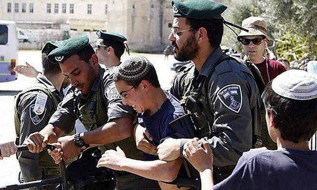 Israeli border policemen hold back a Jewish youth to prevent him from reaching a building occupied by
