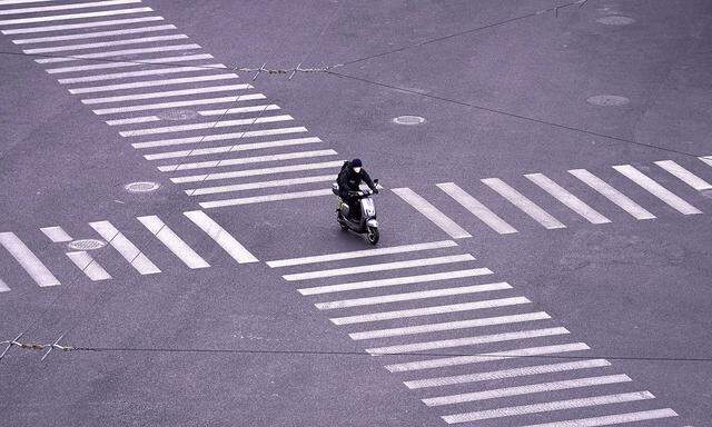 Ein MOpedfahrer mit Schutzmaske in Shanghai