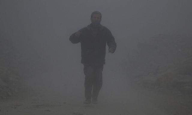 Ein Mann läuft durch die Staubwolke eines Luftangriffs. 