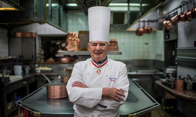 Mit seinen Markenzeichen, Trikolore-Kragen und hoher Kochmütze, wurde er berühmt: Paul Bocuse 2012 in seiner Küche.
