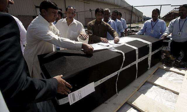 Behörden checken die Papiere eines Sarges, der in Lahore, Pakistan, eingetroffen ist.