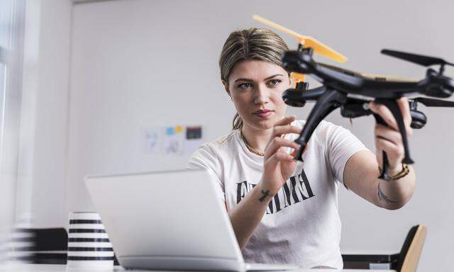 Young woman with laptop at desk holding drone model released Symbolfoto property released PUBLICATIO