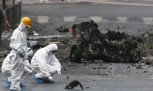 Forensic experts search for evidence amid the debris on a street where a car bomb went off in Athens