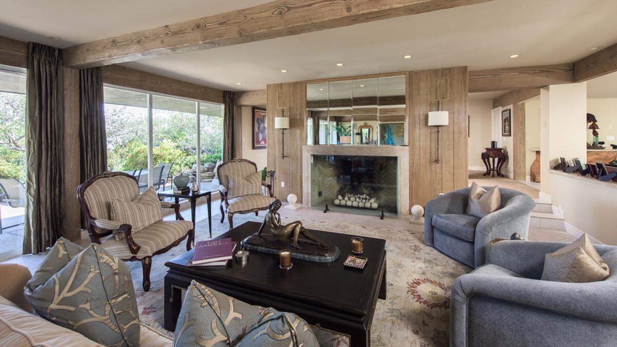 Ein weitläufiges, offenes Wohnzimmer mit Kamin und rustikalen Holzbalken wartet auf den künftigen Eigentümer.