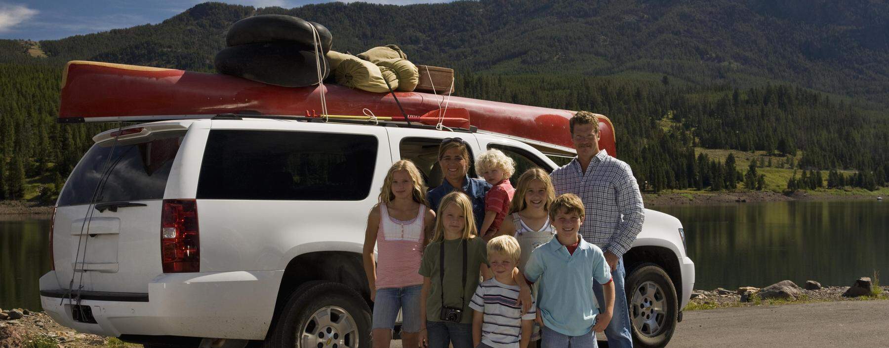 Idylle eines Roadtrips: US-Familie vor ihrem vollgepackten Full-size-SUV. 