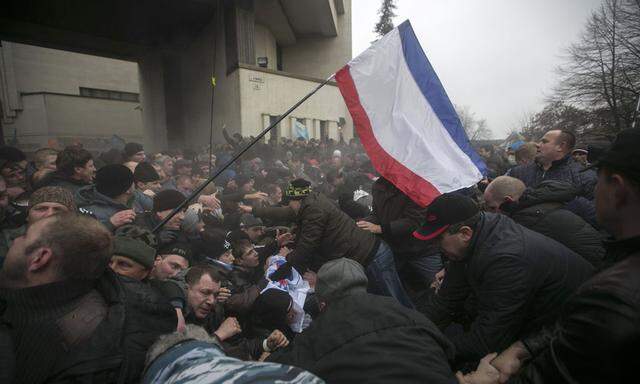 Ukrainian men help pull one another out of a stampede during clashes in Simferopol