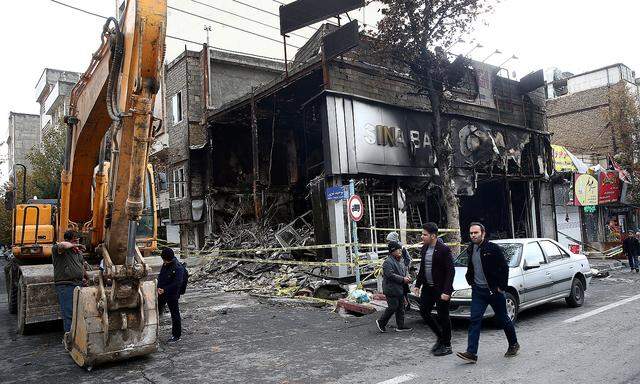 FILE PHOTO: People walk near a burnt bank, after protests against increased fuel prices, in Tehran