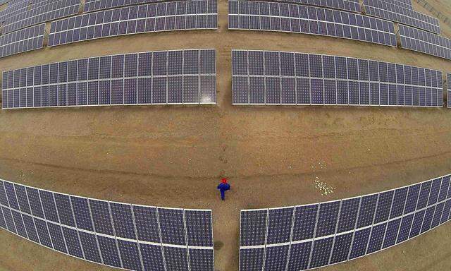 A worker inspects solar panels at a solar farm in Dunhuang