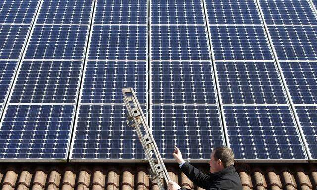 Michael Greif controls his 56 photovoltaic (solar) panels at the roof of his house in Coburg