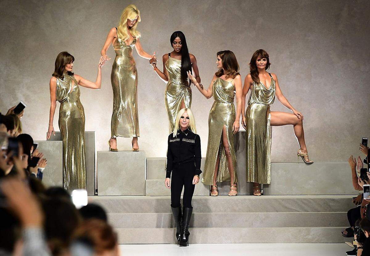 Ein perfektes Kunststück für Donatella Versace (vorne in Schwarz), die sich auch bei der Kollektion für eindeutige Bekenntnisse an die 1990er-Jahre entschieden hatte: Ikonische Versace-Muster aus dieser Ära hatte sie dafür wieder aus dem Schrank geholt. Sie widmete die Frühlingskollektion 2018 ihrem Bruder Gianni Versace.