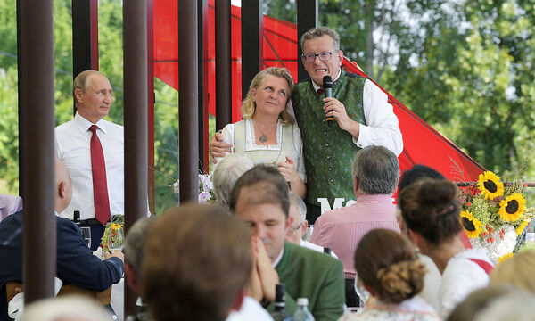 Austria's FM Kneissl is embraced by her groom Meilinger during their wedding celebrations as Russia's President Putin looks on in Gamlitz
