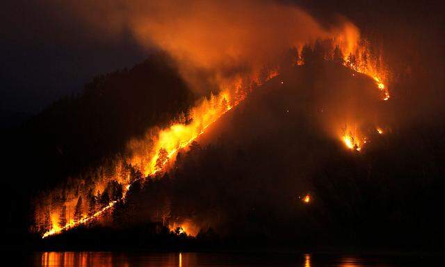 FILE PHOTO: Dry grass, bushes and trees burn on the bank of the Yenisei River in Taiga district