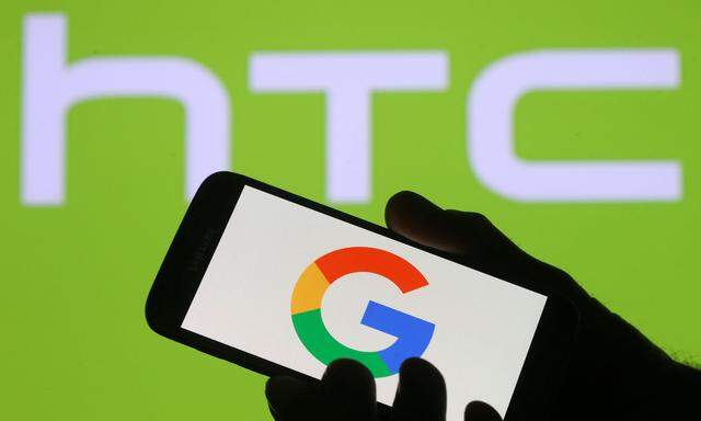 The Google logo is seen on a smartphone in front of a displayed HTC logo in this illustration