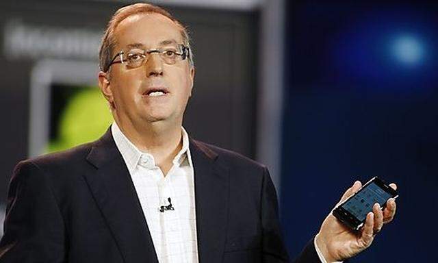 Otellini, president and CEO of Intel Corporation, holds an Intel smartphone reference design as he gi