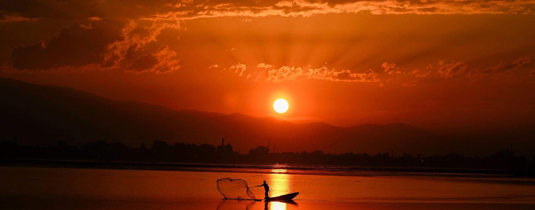 TOPSHOT - A fisherman casts his net in Dal Lake during sunset in Srinagar on September 28, 2023. (Photo by TAUSEEF MUSTAFA / AFP)