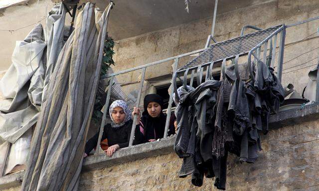 Women look out from a damaged balcony after an air strike on the rebel held al-Saliheen district in Aleppo
