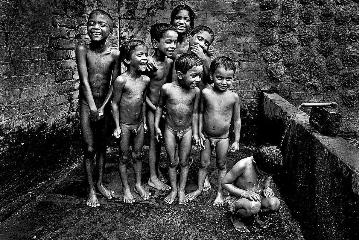 Raghuranjan Sarkar, Indien: "Friends Look"  Lachende Kinder spielen am Straßenrand mit Wasser. Sie warten geduldig, bis der nächste von ihnen an der Reihe ist.