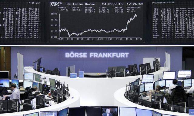 Traders are pictured at their desks in front of DAX board at Frankfurt stock exchange