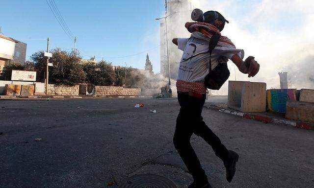 Ein junger Palästinenser wirft Steine auf israelische Polizisten.