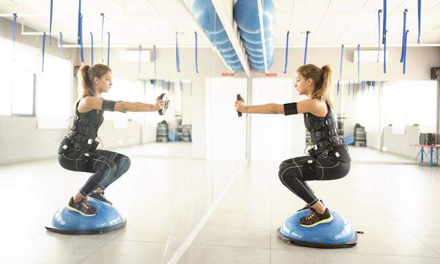 Woman training with electrical muscle stimulation in front of mirror model released Symbolfoto prope