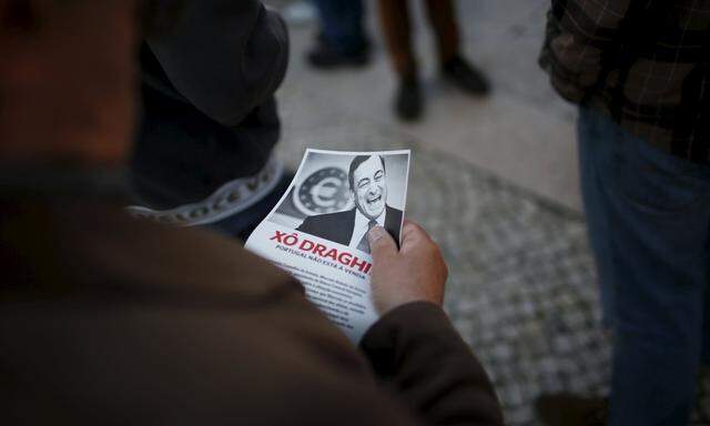 A demonstrator reads a pamphlet during a protest against the visit of European Central Bank (ECB) President Mario Draghi in Lisbon