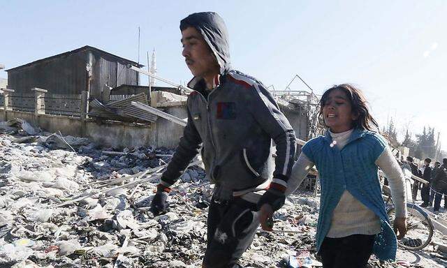 A man holds the hand of a girl as they rush to leave a site hit by what activists said was shelling by forces loyal to Syria's President Bashar al-Assad in Aleppo's al-Sakhour district