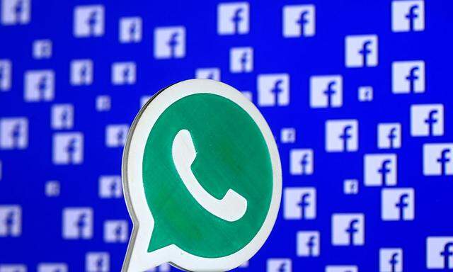 A 3D printed Whatsapp  logo is seen in front of a displayed Facebook logo in this illustration taken 