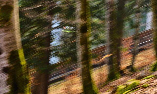 Stefan Kraft springt durch den grünen Wald.
