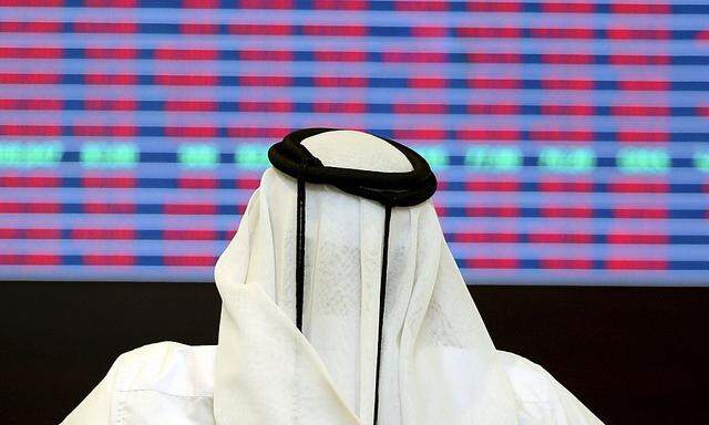 A trader looks at share prices on an electronic display at the Doha Stock Exchange 