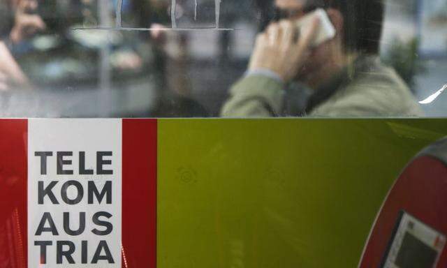 A man makes a phone call behind a sign of Telekom Austria in Vienna