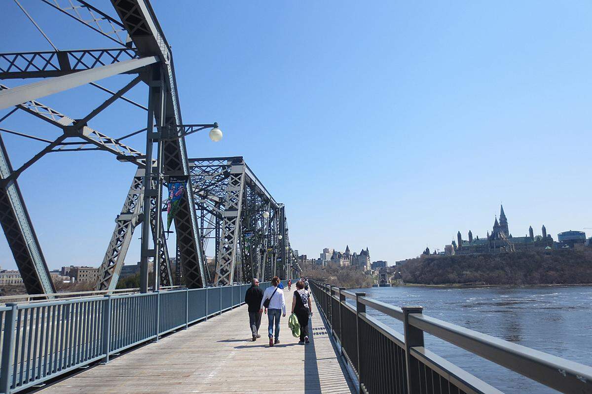 Wer genau hinblickt: Links das Château Laurier, rechts das Parlament, ein Blick von der Brücke in den Bundestsst Ontairo, in dem die hübsche Hapotstadt liegt. Auf der rückwärtigen Seite befindet sich die Schwesterstadt Gatineau, einst Hull, bereits in der Provinz Québec. Der Fluss heißt übrigens Ottawa.