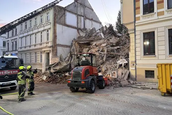 Einsatzkräfte von Polizei und Feuerwehr stehen in der Nähe eines eingestürzten Hauses in Görlitz.