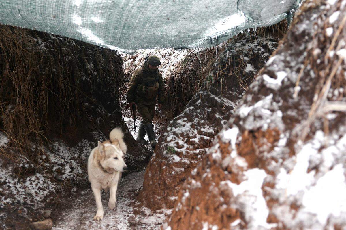 14. Dezember. Ein ukrainischer Soldat und ein Hund in einem  Schützengraben nahe der von Russland besetzten Stadt Horliwka bei Donezk.