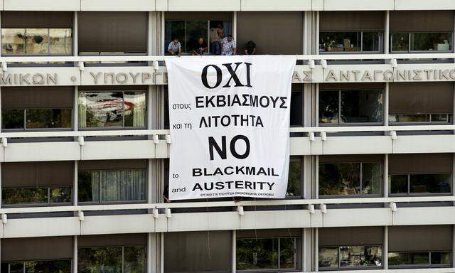Employees of the Ministry of Finance and National Economy stand by a banner unfolded from a balcony of the Finance Ministry in Athens