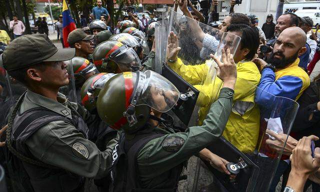 Polizisten drängen Demonstranten in Caracas zurück.