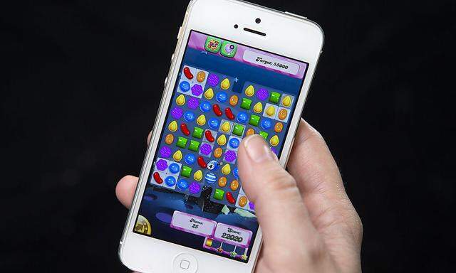 A woman poses for a photo illustration with an iPhone as she plays Candy Crush in New York