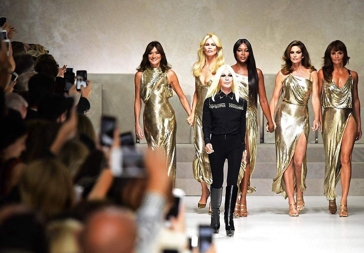 Die hochgeschlitzten, hauchdünnen goldenen Lamé-Kleider, in die die fünf Supermodels gehüllt waren, entsprechen ebenfalls den berühmten, weiblichen Versace-Kleidern und -Silhouetten der Nineties.