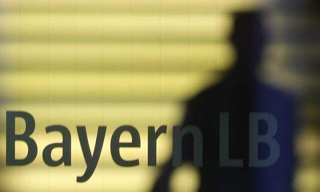 File photo of an employee of the Bavarian public sector bank BayernLB walking near the bank's logo in Munich