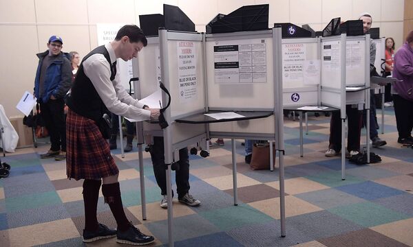 Groups of people vote at a polling station set at a public library in the Mount Pleasant neighborh