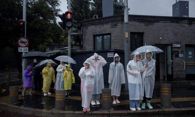 Menschen in Peking versuchen, sich vor dem Regen zu schützen