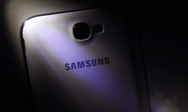 A logo of Apple Inc is reflected next to a Samsung Galaxy Note II smartphone in this photo illustration taken in Beijing