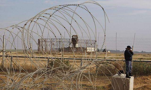 A member of the Hamas security forces stands guard as an Israeli watchtower is seen near the fence between Israel and the southern Gaza Strip