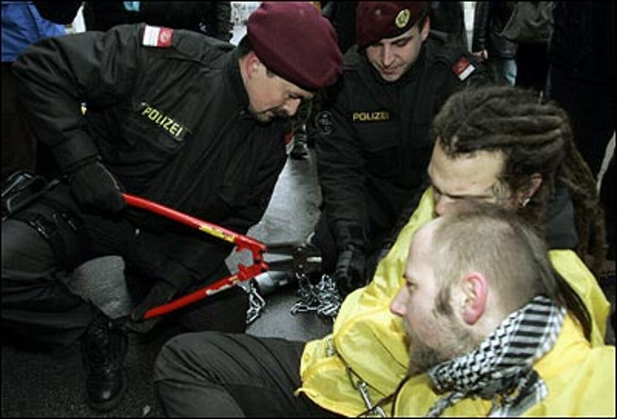 Die Demonstranten hatten sich mit einer schweren Eisenkette vor dem Eingang des Bundeskanzleramtes angekettet und blockierten damit den Zutritt. Auf einem Plakat fordern sie: "Politik für die Bevölkerung - Schluss mit den Lügen".