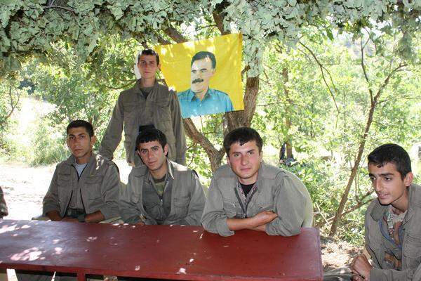Die PKK-Kämpfer verteilen sich nach dem Abzug aus der Türkei in den Bergen im Grenzgebiet. Zwar gilt ein Waffenstillstand, doch das Misstrauen bleibt. Um nicht entdeckt zu werden, sind sie in kleinen Gruppen unterwegs und lagern unter Überdachungen, die sie zum Schutz vor türkischen Drohnen aufgespannt haben. PKK-Chef Öcalan ist allgegenwärtig, blickt von zahlreichen Bildern auf alles, was seine Kämpfer tun.