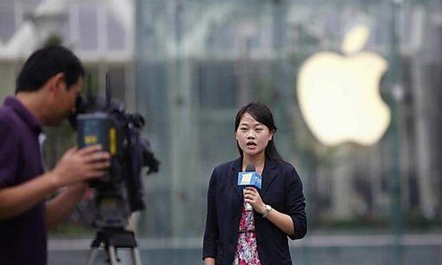 A local television journalist reports in front of an Apple retail store at the financial district in 