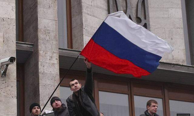 Pro-Russian demonstrators erect a Russian flag outside the regional government building in Donetsk